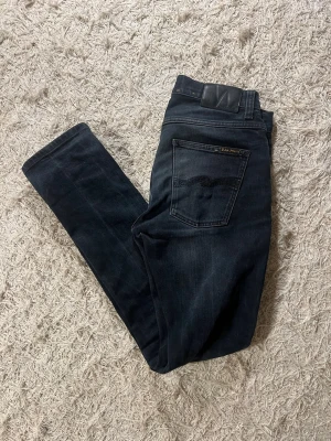 Mörkblå jeans från Nudie Jeans Co - Snygga mörkblå jeans från Nudie Jeans i modellen Grim Tim färgen hidden blue.  Jeansen är slimmade till passformen. Allmänt bra skick utom nudie vågorna på fickorna som ser något slitna ut. 