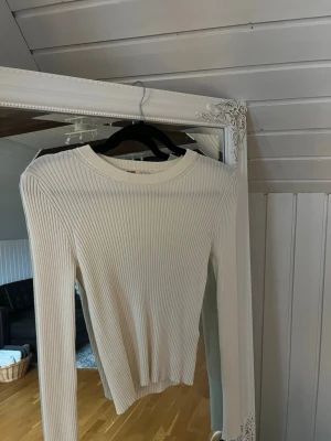 Vit ribbad tröja från Pull&Bear - Säljer en stilren vit långärmad tröja från Pull&Bear i storlek M. Tröjan är ribbad och har en rund halsringning, vilket ger en snygg och enkel look. Perfekt att matcha med jeans eller kjol för en clean vibe.