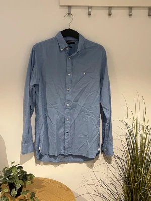 Ljusblå skjorta Tommy Hilfiger - Tommy Hilfiger Ljusblå skjorta. Den är i storlek S och är i fint skick utan några fläckar. På andra bilden ser ni hur den sitter på våran modell som är 179cm. Den tyvärr inte strykt här på bilderna, men självklart gör vi det innan vi skickar iväg den🤟🏻