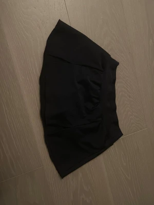 Svart konståknings kjol från Intermezzo - Svart konståknings kortkjol från Intermezzo, tillverkad i Spanien. Kjolen har en enkel design med bred linning och mjukt, stretchigt material i elastan. Passformen är normal och kjolen har en stilren look utan mönster eller extra detaljer.