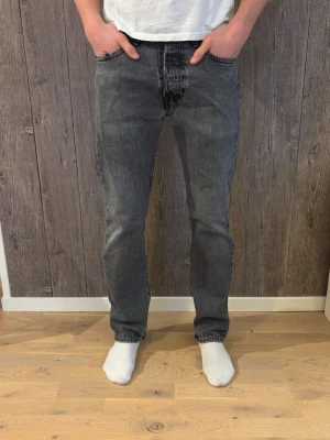 Levi's 501 grå jeans straight fit - Grå Levi's 501 jeans med klassisk straight fit och fem fickor. Jeansen har en mörkgrå tvätt. Dåligt skick! Storleken är 30/32