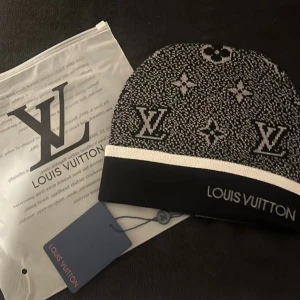  svart och vit mössa - Snygg svart och vit mössa från med klassiskt mönster och logga framtill. Mössan har en bred vit kant och är tillverkad i mjukt material som håller dig varm och stilren under kalla dagar.