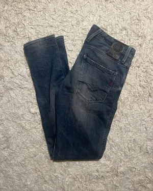 Replay jeans blå waist 30/32 - Snygga jeans från Replay i modellen anbass med klassisk femficksdesign och diskreta slitningar. Modellen har raka ben och normal passform, med mörk tvätt. Perfekta för dig som gillar stilrena jeans. Inga tecken på användning. 