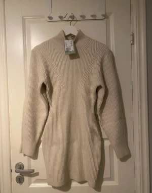 Figursydd vinterklänning - Figursydd klänning i halvpolo i färgen naturvit. Säljs inte längre på h&m. Stretchig, skön och varm.   Material Polyester 54%, Akryl 41%, Ull 5%  Köpt för 449kr