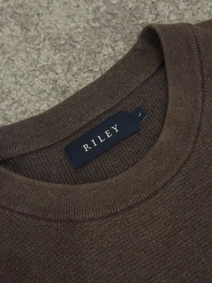 Brun stickad tröja från Riley - Säljer en riktigt snygg brun stickad tröja från Riley i storlek L. Tröjan har rund halsringning och är långärmad. Perfekt för lager-på-lager och enkel att matcha med jeans eller chinos. Inga defekter någonstans. Köpt på Brothers för nypris: 699kr, mitt pris: 499kr.     Bara att höra av sig vid frågor.