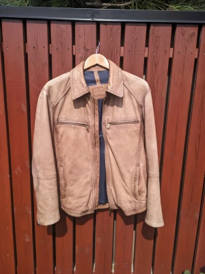 Massimo Dutti, skinnjacka, lammnappa, storlek M, brun - Skinnjacka i lammnappa från Massimo Dutti. Färgen är brun och nyansen är mörkare än vad bilden visar. Ett mindre mörkare parti i nacken (bild 5) efter användning/UV som syns mest på nära håll och givetvis inte alls när jackan bärs. I övrigt fint skick. Ordinarie pris c:a 4200 kr.  Bröstmått (armhåla till armhåla): 110 cm. Längd (krage till fåll): 67 cm.  Vid frågor kontakta mig gärna via chatt eller epost.