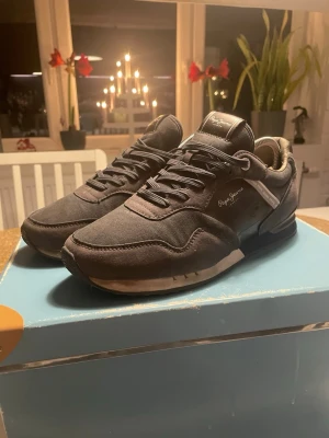 Svarta sneakers från Pepe Jeans - Snygga svarta sneakers från Pepe Jeans med rund tå och platt sula. Ovandelen är i mocka och skinn med coola sömmar och logga på sidan och hälen. Skorna har snörning och en slitstark gummisula med mönster för extra grepp. Perfekt för dig som gillar stilrena och bekväma sneakers.(kan skicka bild på mer) man får box