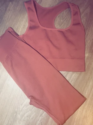 Rostfärgat ribbat underklädesset - Säljer ett snyggt tvådelat underklädesset i rostfärg. Setet består av en ribbad sport-bh med breda axelband och matchande höga trosor. Materialet är stretchigt och mjukt, perfekt för en bekväm känsla hela dagen. Inga synliga loggor eller märken.