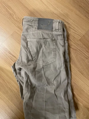 Jacob Cohen w36 - Snygga beige jeans från Jacob Cohen med klassisk femficksmodell och raka ben. Jeansen har diskret logga på bakfickan och patch i midjan. Tillverkade i mjuk bomull för skön känsla och stilren look.