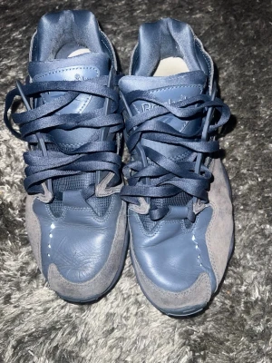 Blå sneakers från Reebok - Snygga blå sneakers från Reebok med cool design. Skorna har ovandel i både skinn och mocka, samt klassisk snörning. Mörkblå färg med ljusare gråblå detaljer och rund tå. Perfekta för dig som gillar streetstyle och sportig look.