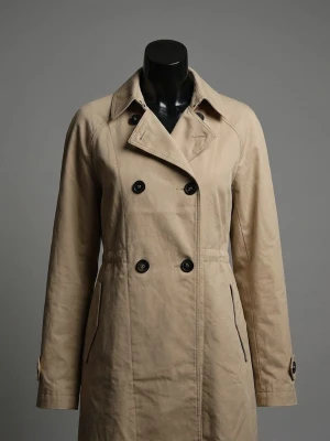 Beige trenchcoat med knappar - Stilren beige trenchcoat med dubbelknäppning och klassisk krage. Jackan har långa ärmar, fickor med dragkedja och snygga detaljer vid kragen. Perfekt för dig som vill ha en tidlös look.