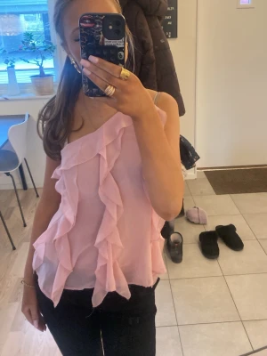 Rosa oneshoulder volangtop - Söt rosa oneshoulder-top med volangdetaljer framtill. Luftig och lätt modell som ger en romantisk vibe. Perfekt för dig som gillar att sticka ut med en feminin touch.