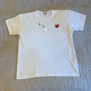 Comme des Garçons T-shirt  - Säljer nu en sjukt snygg vit Comme des Garçons t shirt 🌟 | Storlek: L (små i storlekarna) motsvarar mer än M | Hyfsat bra skick 7/10 (finns en liten gul fläck) | Tags finns och är påsatt | Köpt på NK (har bevis) | Nypris ligger på 1000kr | Sjävklart ÄKTA | Hör av dig vid minsta fundering! | A&Wfashion 🙌🏻