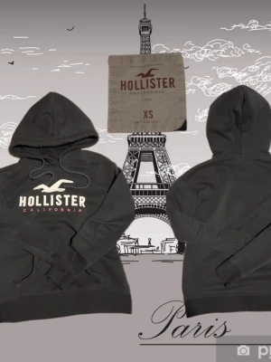 Svart vintage Hollister hoodie med logga XS - Snygg svart vintage  hoodie från Hollister i storlek XS. Klassisk modell med stor vit Hollister-logga och texten CALIFORNIA i rött framtill. Mjuk bomullsblandning, huva med dragsko och känguruficka. Perfekt för en chill och avslappnad stil.