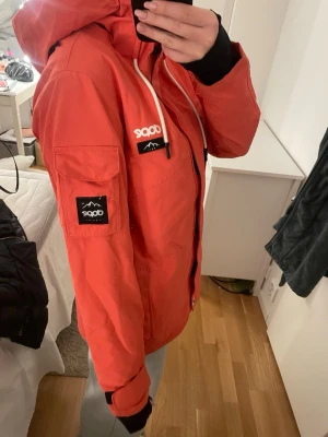  Skid jacka från Dope - Snygg skidjacka från Dope med huva, dragkedja och vita snören. Jackan har svarta detaljer, patchar på bröstet och ärmen samt flera fickor. Färgen är annorlunda på kameran än va de är i verkligheten, sista bilden är mer hur den ser ut😊