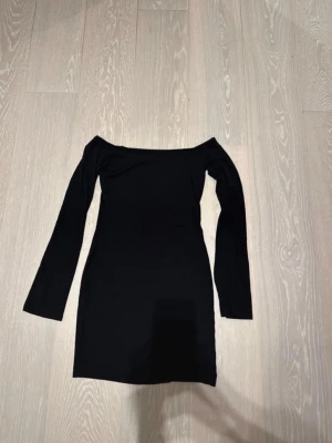 Svart offshoulder kortklänning - Säljer en svart, tight och stilren kortklänning med offshoulder-modell och långa ärmar från Gina Tricot. Använd ett fåtal gånger och är i jättebra skick