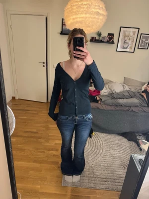 figursydd cardigan - Vero Moda - En svart, figursydd cardigan från Vero Moda Basic. Ett absolut måste i basgarderoben! Den har en djup V-ringning och knäppning hela vägen fram. Storleken är M men passar en S/XS • Material: 100% bomull (andas och håller formen bra).