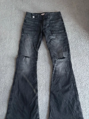 Svarta bootcut jeans Gina Tricot - Säljer ett par svarta bootcut jeans från Gina Tricot i storlek 164. Jeansen har slitningar och hål, de är knappt använda och är i mycket bra skick. De är låga i midjan.