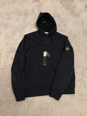 Marinblå stone island hoodie - Denna hoodie är ett måste för dig som uppskattar kvalitet och tidlös design. Storlek S. Den är i mycket bra skick och tags medföljer✅ Perfekt för både vardagsbruk och mer avslappnade tillfällen. Tillverkad i högkvalitativa material som ger en bekväm passform och lång hållbarhet. En klassiker som aldrig går ur tiden! Skriv vid minsta fråga eller funderingar!