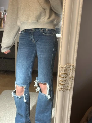 Blå bootcut jeans från 157 Paris Core - Säljer ett par blå jeans från Lager 157 Paris Core med bootcut passform och slitna hål vid knäna. 