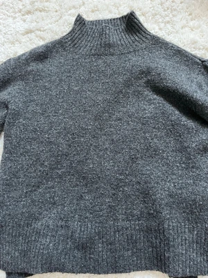 Mörkgrå stickad polotröja Gina Tricot - Mysig mörkgrå stickad polotröja från Gina Tricot. Tröjan har hög ribbad krage, långa ärmar och slits i sidorna. Perfekt för kyliga dagar och enkel att styla med dina favoritjeans eller kjol.super mysig!❣️❣️