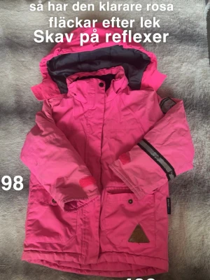 Rosa jacka med reflexdetaljer - Säljer en knallrosa parkajacka från om the peak med huva och reflexdetaljer på ärmen. Jackan har stora fickor framtill, kardborre vid ärmslut och dragkedja med knappslå. Perfekt för kyliga dagar och enkel att röra sig i.🌸 Luvan har inte alltid används så den är mer klar rosa. Fläckar efter lek. Skav på reflexer. Storlek 98