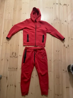 Nike tech fleece och byxor röd - Röd nike tech fleece och byxor kommer tillsammans använda  4 gånger har inte använding av de längre och är nytt skick i storlek XL 158-170 cm tar även emot trades mot andra klädesplagg 