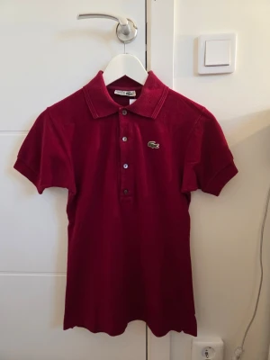 Lacoste Pikétröja  - Vinröd Pikétröja från Lacoste i mycket fint skick. Hel logga ✅️ Bekväm ✅️ Sällan använd ✅️ Vid köp av 2 eller fler produkter skickas ordrarna samma dag annars skickas ordern nästkommande dag. OPS! På min profil finns det 2 till pikétröjor från Lacoste alla tre tröjor kan köpas för 900:-. Styck pris: 300:-