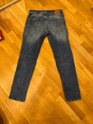 Jack & Jones Tapered Mike jeans 30/32 - Säljer ett par blå jeans från Jack & Jones, modell Tapered Mike. Jeansen har en snygg tvätt med ljusa partier och klassiska fem fickor. De är tillverkade i bomull och har en tapered passform som smalnar av nedtill. Perfekta för dig som gillar en modern och avslappnad stil.