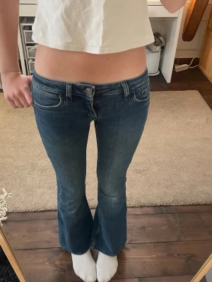 Blå low waist jeans - Säljer ett par blå flare jeans från BDG Urban Outfitters. De har låg midja och klassisk femficksdesign. Jeansen är i stretchig denim och har en riktigt schysst bootcut passform. Jag valde att sälja dem för att dem inte passar längre. 
