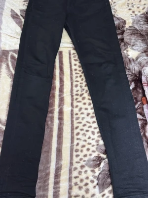 Svarta skinny jeans - Svarta jeans med slim passform och klassisk femficksdesign. Byxorna har en smal siluett hela vägen ner och är tillverkade i ett stretchigt jeansmaterial som sitter tajt mot benen. Perfekta för dig som gillar en stilren och enkel look.