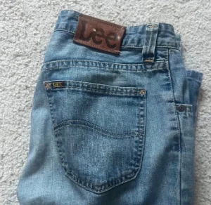 Low waisted lee jeans  - Snygga blå jeans från Lee med klassisk bootcut-passform och normal midja. Jeansen har fem fickor, bälteshällor och Lee-logga på bakfickan samt läderpatch bak. Materialet är slitstarkt denim i bomull. Perfekta för dig som gillar retrovibbar och bredare ben.