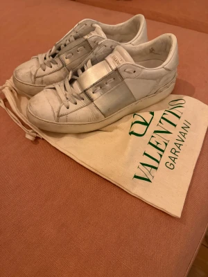 Valentino Garavani vita sneakers - Säljer ett par vita Valentino Garavani sneakers med silverfärgad detalj över snörningen. 