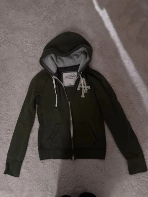 Grön zip up Hoodie Abercrombie & Fitch  - Mörkgrön zip up hoodie ifrån Abercrombie & Fitch i storlek M! 
