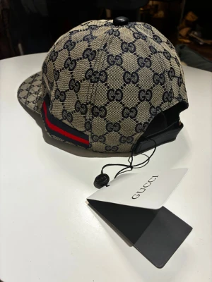 Gucci keps - Gucci keps beige och blå med klassiskt monogram GG-mönster. Onesize justerbar rem baktill. Aldrig använd, helt ny. 