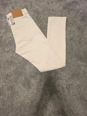 Vita jeans från Tiger of Swede W29 L32 - Snygga vita jeans från Tiger of Sweden med ett ljusbrunt Tiger of Sweden-läderpatch bak. De är tillverkade i mjukt bomullsmaterial. Perfekta för dig som gillar stilrena och fräscha looks.