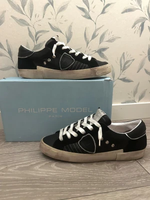 Philippe Model svarta sneakers 🛡️ - Svarta Philippe Model sneakers🛡️ med krom detaljer och vita snören. Skorna är i skinn och mocka, samt silverfärgade nitar på sidan. Snygg kontrast mellan svart och vitt. Väldigt unika sulor och ett par riktigt feta skor helt enkelt👍🏼Låda kan fås med✅ Bara att skriva vid funderingar, fler bilder kan fås💬 Storlek: 43 Herr