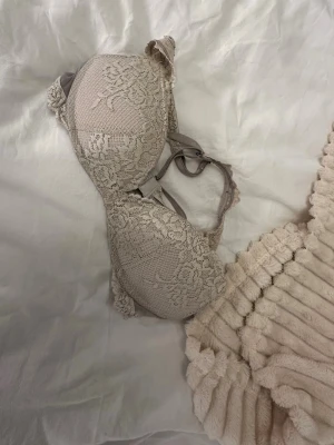 Beige spets bh från Intimissimi - Säljer en beige bh från Intimissimi med vacker spets och blommigt mönster. bhn har justerbara axelband och hakknäppning bak. Perfekt för dig som gillar romantiska detaljer och mjuka färger.