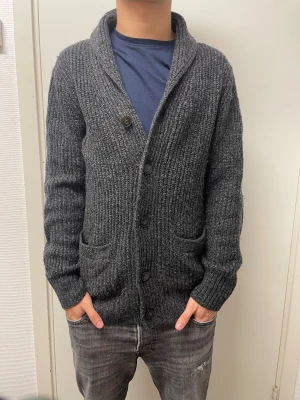 Stickad cardigan - Fet mörkgrå stickad cardigan från H&M. Väldigt bra skick. Modellen är 173cm, 64kg. Pris kan självklart diskuteras!