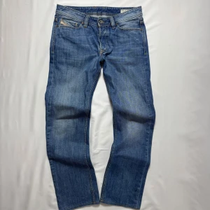 Diesel Jeans - Klassiska blå jeans från Diesel, modell Larkee. Jeansen har raka ben, fem fickor och snygga kontrastsömmar. Tillverkade i slitstark bomullsdenim med diskret tvättad look och detaljerade nitar. Perfekta för dig som gillar en tidlös och avslappnad stil.