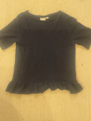 Topp med smock på magen - Fin topp som är marinblå och som har smock på magen