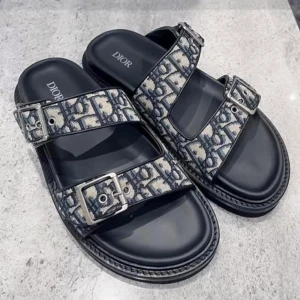 Dior sandaler med mönstrade remmar - Snygga sandaler från Dior med två breda remmar i blått och beige mönster, justerbara med silvriga spännen. Modellen heter Alias Slides och är väldigt populära. Perfekta för dig som vill ha något extra till sommaren. Dessa är i storlek EU 42.