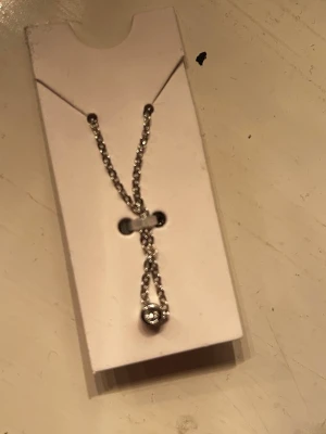 Silverfärgad halsband med liten diamant  - Säljer en unik silverfärgad halsband med en liten rund diamant