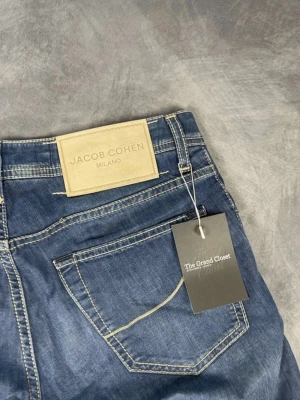 Blå jeans från Jacob Cohën Milano - Snygga blå jeans från Jacob Cohën Milano med klassisk femficksdesign och kontrastsömmar. Jeansen har en rak passform och är tillverkade i mjukt bomullsmaterial. Perfekta för dig som gillar stilrena och tidlösa jeans med exklusiv känsla.