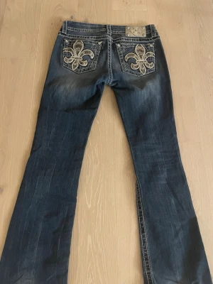 Snygga Miss Me bootcut jeans - Snygga mörkblå bootcut jeans från Miss Me med broderade detaljer och paljetter på bakfickorna. Säljer pga att dem är för stora för mig och kommer därför inte till användning. Jag brukar oftast ha xs i jeans så ni kan utgå från ngt💗 .Dem är i bra skick men har ändå används och eftersom dem är för långa för mig har dem lite slitage nere på byxbenen som man kan se på på bild 6.  Älskar verkligen dem här och har fått mkt komplimanger!