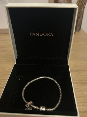 Pandora berlock Armand  - Jätte fint skick! Knappt använt den! Med följer en berlock som ska föreställa en blombukett med roset på.