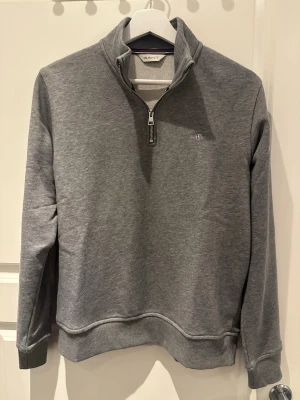 Grå halv zip tröja från Gant - En grå halv zip tröja från Gant i storlek 176. Passar även som S.