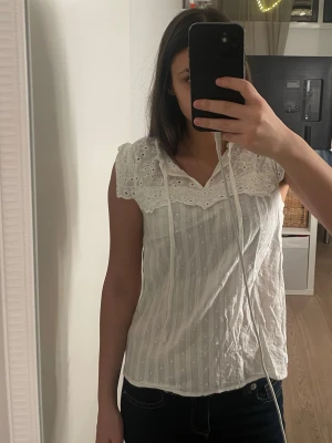 Vit blus med spets från SHEIN - Säljer en vit blus från SHEIN i storlek M. Blusen har spetsdetaljer upptill, knytband vid halsen och är kortärmad. Materialet är lätt och luftigt med diskreta prickar och ränder i tyget. Perfekt för vår och sommar!