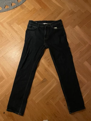 Marinblå jeans från Vailent W32 L32 - Säljer ett par marinblå jeans från Vailent i regular fit, storlek W32 L32. Klassisk femficksmodell med raka ben och snygga kontrastsömmar. Perfekta för dig som gillar enkel och stilren look. Materialet är slitstarkt jeans och midjan är normal.