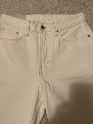 Jeans från H&M - Säljer ett par vita loose fit jeans från H&M i storlek 29/32. Byxorna har klassisk femficksdesign, raka ben och är tillverkade i bomull. Perfekt för dig som gillar en avslappnad och trendig stil. Dragkedja och knapp framtill. Knappt använda